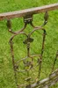 A close-up of a decorative metal railing with ornate scrollwork and floral motifs, set against a blurred green grassy background. Anteprima dell’immagine prodotto