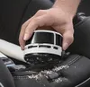 A hand is using a mini vacuum cleaner to clean crumbs from a car seat. Anteprima dell’immagine prodotto