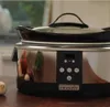 A Crockpot slow cooker is shown on a wooden table, with a window in the background. Produktbild-Vorschau