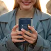 A person holding a smartphone with a wallet case. Voir les images du produit