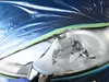Close-up of a car headlight being worked on, with protective plastic sheeting and a tool. Podgląd zdjęcia produktu
