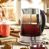 A glass electric kettle filled with tea sits on a wooden table next to a book and an orange mug, with a window and autumn foliage in the background. Anteprima dell’immagine prodotto