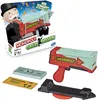 The image shows the packaging of a Monopoly money-shooting game, along with some of the game's components. Produktbild-Vorschau