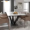 A dining table with a metal spider leg base, surrounded by chairs, set in a modern dining room. Voir les images du produit