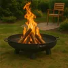 A fire pit with burning logs in a backyard setting with a chair in the background. Produktbild-Vorschau