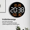 A digital wall clock displaying time, date, temperature, and humidity, mounted on a wall next to a framed picture. Text below describes its features. Produktbild-Vorschau