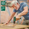 A man is using a cordless drill to screw something into a wooden surface. There are icons in the top left corner indicating battery level and drill function. Produktbild-Vorschau
