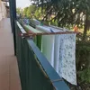 A clothes drying rack attached to a balcony railing, with laundry hanging on it. Voir les images du produit