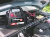 A car engine bay with a jump starter connected to the battery. Anteprima dell’immagine prodotto