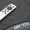 A close-up shot of a white remote control resting on a black vibrating fitness plate with the brand logo visible. Produktbild-Vorschau
