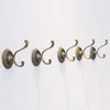 A row of decorative bronze coat hooks mounted on a white wall. Produktbild-Vorschau