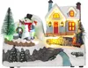 A festive, illuminated Christmas village scene with a house, snowman, children, and a tree. Podgląd zdjęcia produktu