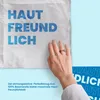 A hand touching a white fabric with blue text, with a blue background. Produktbild-Vorschau