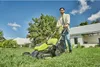 A man is mowing his lawn with a cordless lawnmower on a sunny day. Produktbild-Vorschau