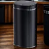 A black sensor trash can is placed on a wooden floor in a kitchen. Náhled obrázku produktu