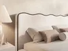 A close-up view of a bed with pillows and a bedside lamp. Produktbild-Vorschau