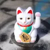 A white Maneki-neko cat figurine with red ears and a green and red collar sits on a textured surface. Produktbild-Vorschau