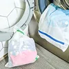 Laundry bags filled with clothes next to a washing machine. Voir les images du produit