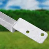 A close-up shot of a galvanized steel post anchor, with two holes for screws, against a blurred background of green foliage and blue sky. Produktbild-Vorschau