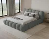 A modern bedroom with a large, plush bed as the focal point, set against large windows with a view of nature. Voir les images du produit