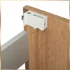 A close-up view of a white plastic mounting bracket attached to a wooden cabinet door. Podgląd zdjęcia produktu