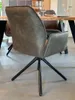 A close-up view of a swivel dining chair with a brown faux leather seat and black metal legs, placed near a wooden dining table. Produktbild-Vorschau