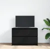 A black TV stand with a black TV on top, placed against a white wall. Náhled obrázku produktu