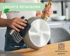 A person is cleaning the bottom of a frying pan with a cloth. Produktbild-Vorschau