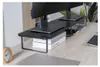 A black monitor stand with two monitors on top, placed on a wooden desk. Náhled obrázku produktu