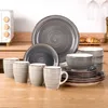 A set of grey and white ceramic dishes and mugs are arranged on a wooden table. Produktbild-Vorschau
