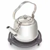 A stainless steel kettle sits on a black cast iron trivet against a white background. Produktbild-Vorschau