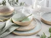 A table setting with plates and bowls, suggesting a meal or dining experience. Produktbild-Vorschau