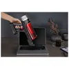 A hand holding a cordless vacuum cleaner over an open laptop on a desk, with a cup of coffee and flowers in the background. Produktbild-Vorschau