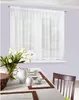 A white sheer curtain hangs over a window, with a dining table set for breakfast in the foreground. Produktbild-Vorschau