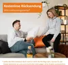 A couple relaxing on a couch, with a pillow between them. There is an orange pillow and a bottle of liquid on a coffee table in the foreground. The background shows a shelf unit with plants and decor. Produktbild-Vorschau