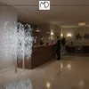 A hotel lobby with a reception desk and seating area, featuring decorative LED trees. Podgląd zdjęcia produktu