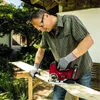 A man is using a jigsaw to cut a piece of wood outdoors. Produktbild-Vorschau