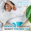 A woman is lying on a bed with a pillow, looking happy and relaxed. Produktbild-Vorschau