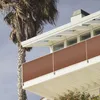 A close-up view of a balcony with a brown privacy screen and a palm tree in the background. Anteprima dell’immagine prodotto