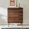 A wooden dresser with four drawers stands against a grid-patterned wall. Produktbild-Vorschau