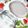 A close-up shot of a glass jar lid and the rim of a glass jar, surrounded by floating ingredients like tomatoes, onions, and cucumber. Voir les images du produit