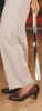 A person is using a long shoehorn to put on a brown high-heeled shoe. Produktbild-Vorschau