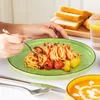A person is eating spaghetti from a green plate, with toast and a drink in the background. Náhled obrázku produktu