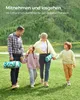 A family walks across a grassy field, carrying rolled-up picnic blankets. Produktbild-Vorschau