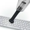A mini vacuum cleaner with a brush attachment is being used to clean a computer keyboard. Produktbild-Vorschau