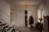 A well-lit hallway with a staircase, bicycle, coat rack, and a shoe shelf. Produktbild-Vorschau