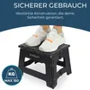 A black foldable step stool with two white sneakers standing on top, in front of a dark blue banner with text. Produktbild-Vorschau