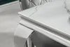 A close-up of a modern dining table with a white marble-patterned glass top and chrome legs. Náhled obrázku produktu