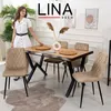 A woman is standing next to a dining table set with chairs, placemats, and a vase with dried flowers. Produktbild-Vorschau