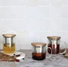 Three glass tea mugs with bamboo lids and metal infusers are arranged on a counter with a tiled backsplash. Voir les images du produit